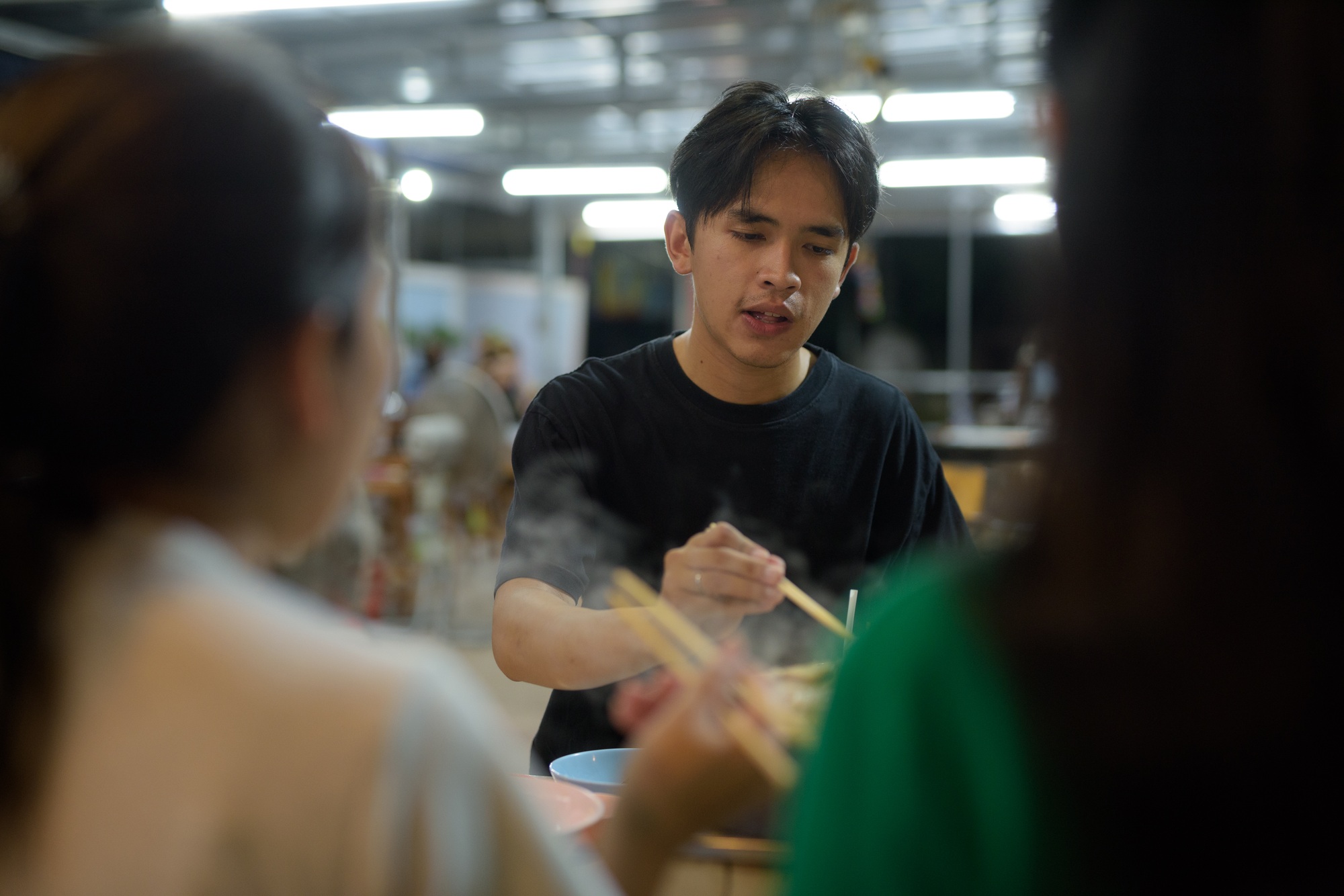 Thai man eating Thai Food BBQ Grill Mu Kratha at night with friends